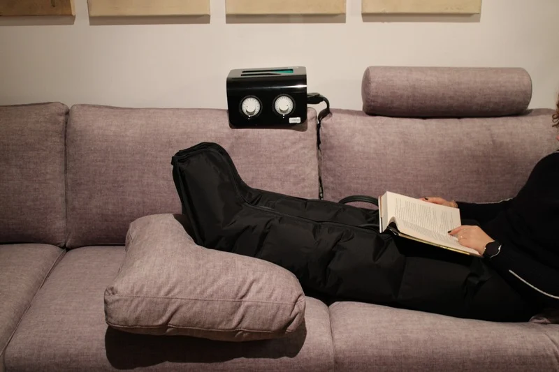 Equipo de presoterapia siendo usado por una persona estirada en el sofá